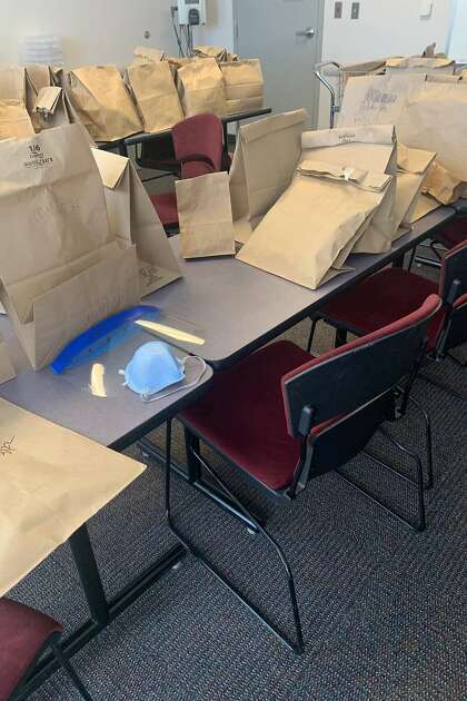 Brown bags containing masks and face shields for individual nurses. Mawata Kamara is a nurse at two Bay Area hospitals. She's an emergency room bedside nurse at San Leandro Hospital, a public facility. She also works in ICU of a private hospital, which she can't name, as a nurse. Mawata directly experiences the mask shortage impacting frontline workers. At the private hospital she has one mask she must reuse over and over and and keeps it in brown paper bag with her name on it at hospital so no one takes it.