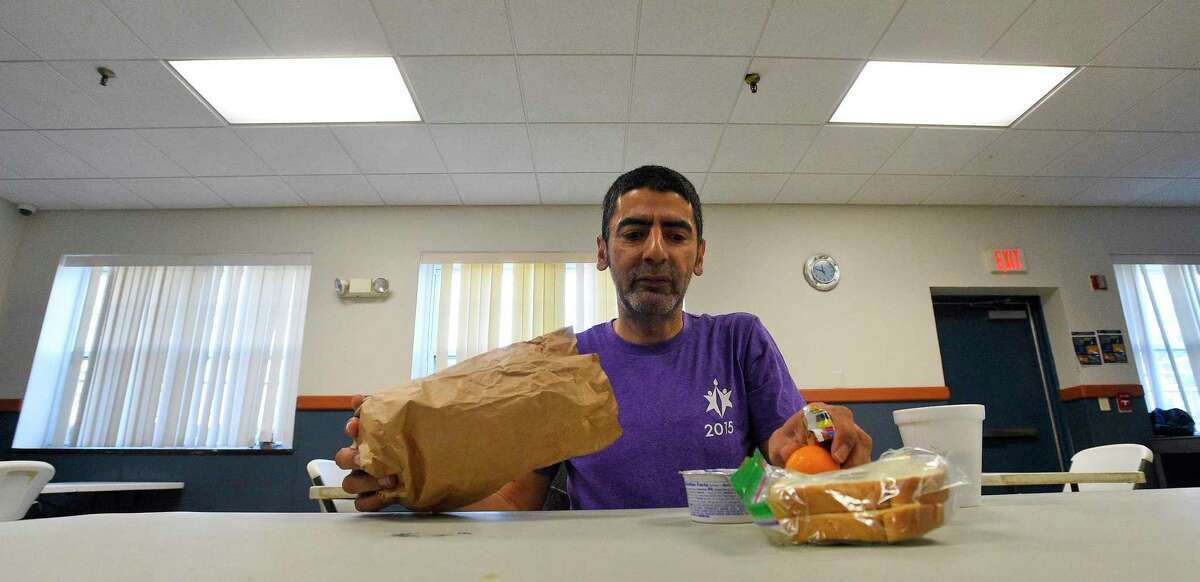 Jose Lopez, a guest of Pacific House, unpack a bag lunch he received at the homeless shelter on Friday in Stamford. Pacific House staff are providing a safe enviorment for its guests by serving breakfast, lunch and dinner in shifts, limiting seating to small groups of two at a table and spacing the tables further apart.