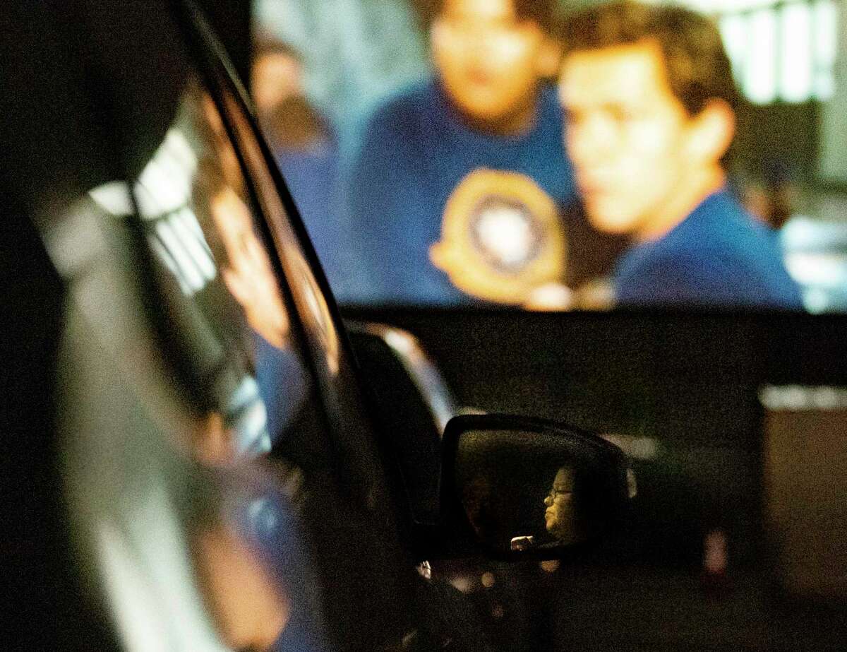 Kim Taylor is reflected in a rear-view mirror while watching a movie projected outdoors at the EVO Entertainment facility in Schertz on Friday night, March 27, 2020. The EVO Drive-In showed "Spider-Man Homecoming," free of charge, although patrons were encouraged to buy food and beverage to support employees working the show. The event provided a chance for people to see a movie while maintaining social distancing to combat the spread of the coronavirus.
