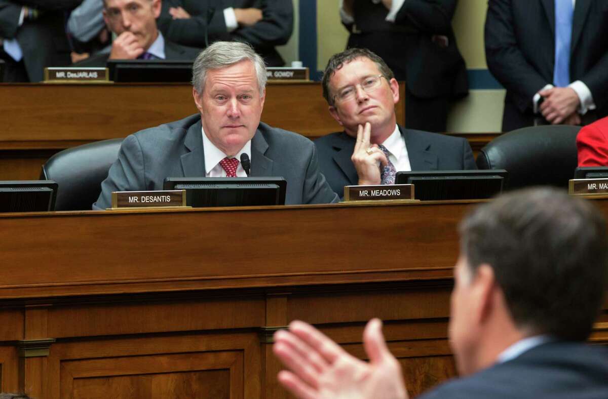 In this file photo from Thursday, July 7, 2016, Rep. Mark Meadows, R-N.C., left, and Rep. Thomas Massie, R-Ky., listen to FBI Director James Comey during a House Oversight Committee hearing at the Capitol in Washington. Meadows, currently President Donald Trump's acting-chief of staff, is still the sitting representative of North Carolina's 11th Congressional District in the House of Representatives as the body prepares to vote on massive relief funding to fight the Covid-19 pandemic, Friday, March 27, 2020. Party leaders had hoped to pass the measure by voice vote without lawmakers having to take the risk of traveling to Washington, but that plan might be complicated by Massie who could force a roll call vote. (AP Photo/J. Scott Applewhite, file)