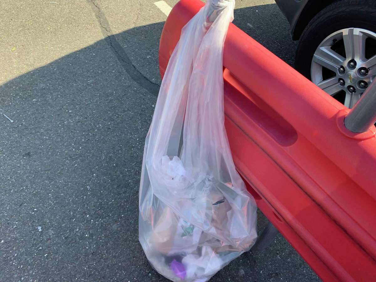 Araceli Bermudez of Bridgeport took off her gloves in the parking lot of Shelton’s Shop Rite and dropped them in this bag attached to a shopping cart retrieval center.
