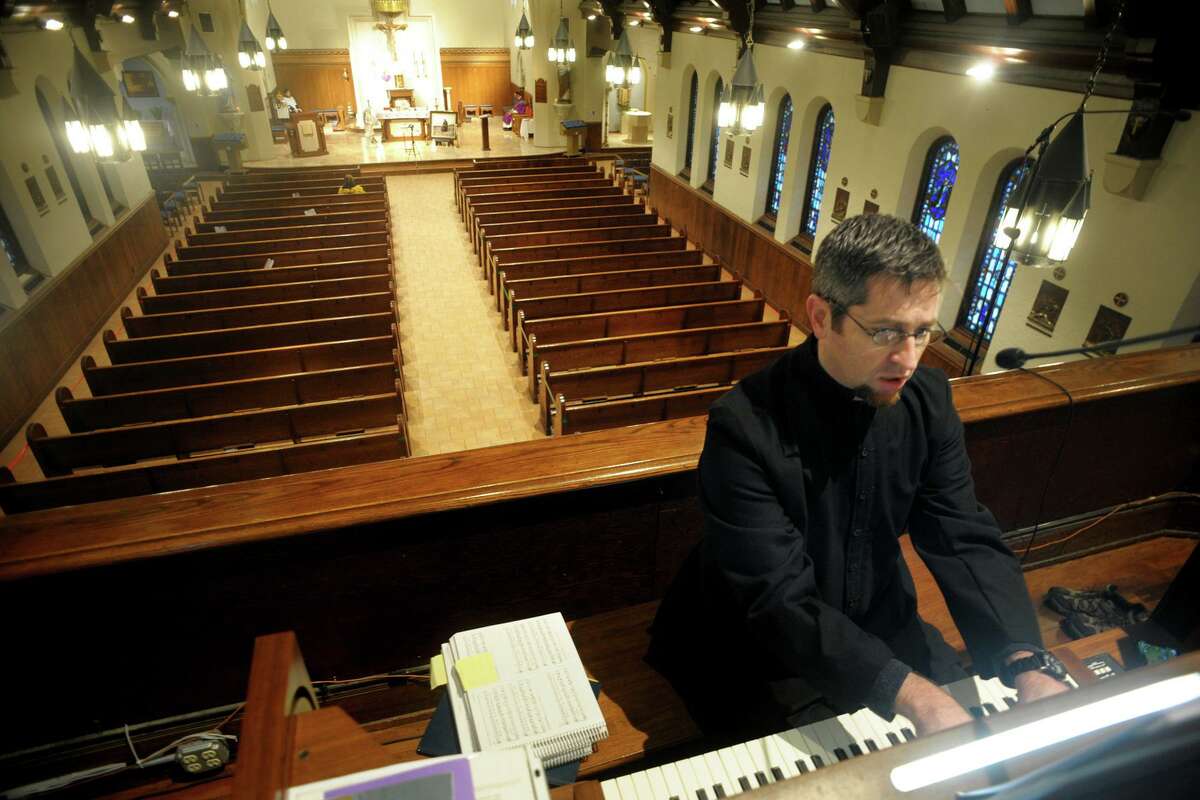 With an empty sanctuary behind him, music director Mac Cooney plays organ and sings during a Sunday mass at Our Lady of Assumption Church, in Fairfield, Conn. March 29, 2020. The church has been live steaming several masses a week for parishioners since the church has been closed to the public due to coronavirus precautions.