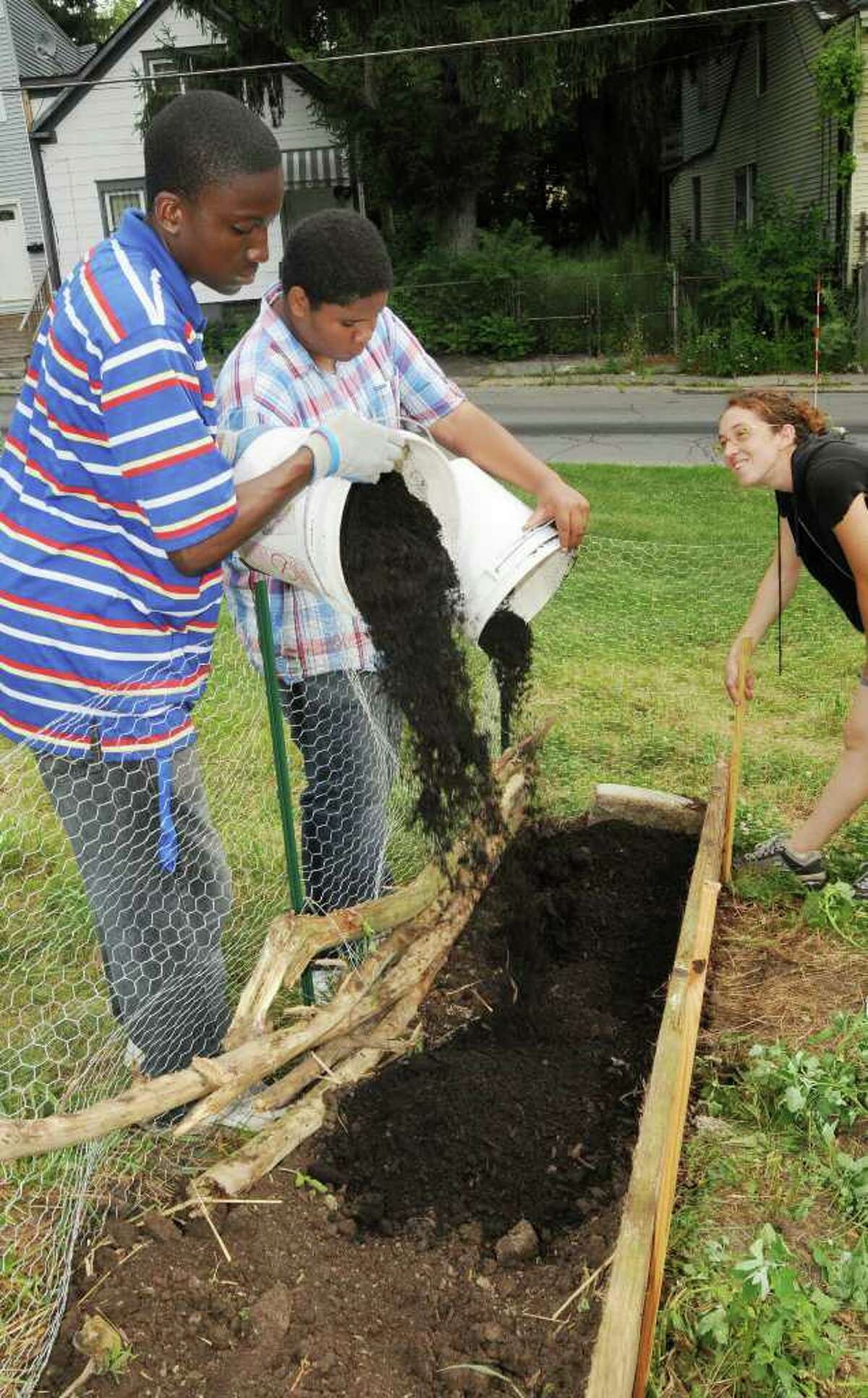 Akil Hamilton, 17, Dedree Clarke, 15, and Rana Morris install a garden box intended to house snap peas. (Luanne M. Ferris / Times Union)