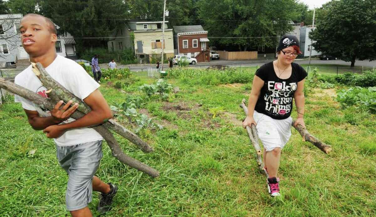 Anthony Ballou, 15, and Jessica Quinlan gather tree limbs for the fence. (Luanne M. Ferris / Times Union)