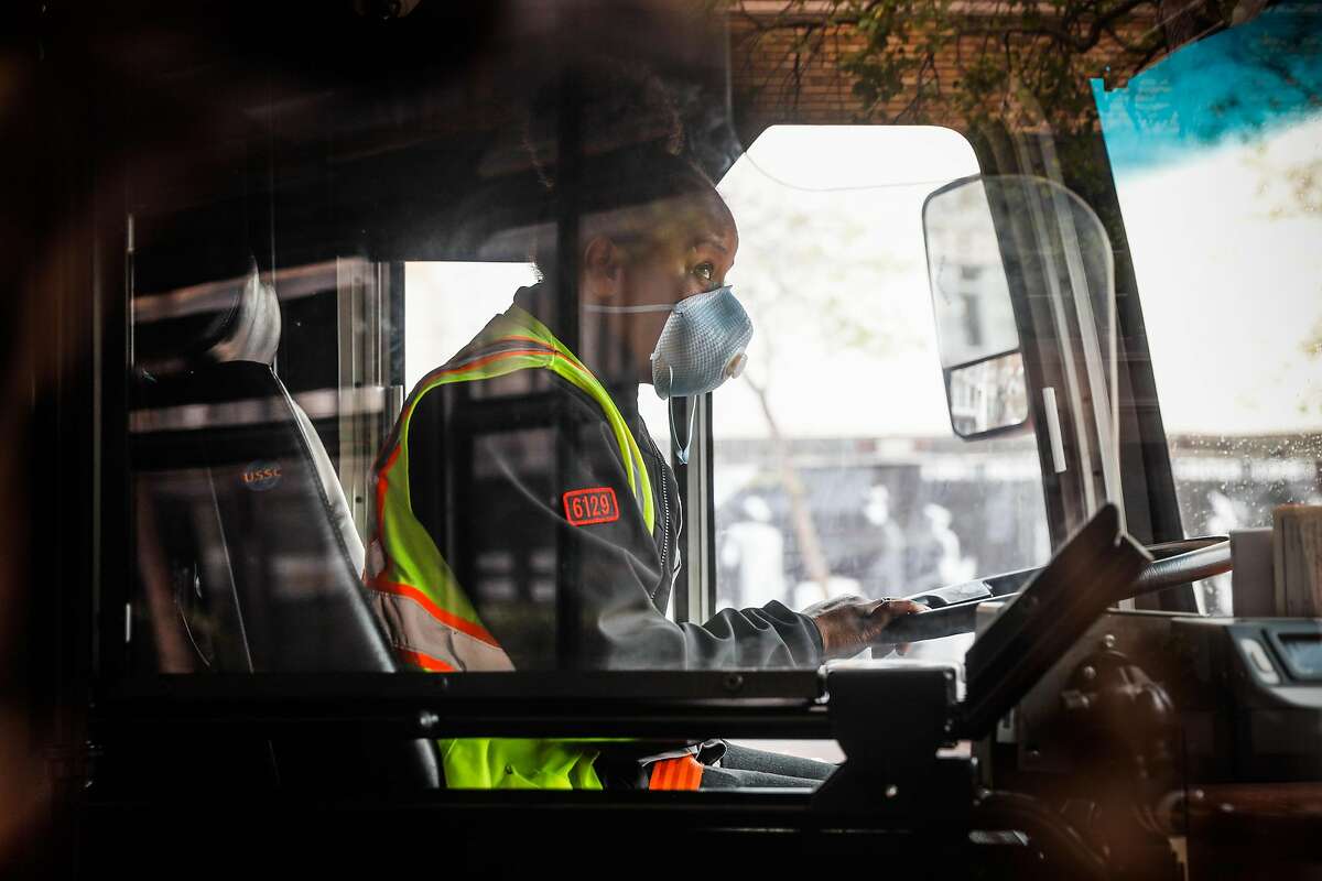A MUNI bus driver wears a mask while driving on Market Street during the second week of shelter in place orders due to the coronavirus on Sunday, March 29, 2020 in San Francisco, California.