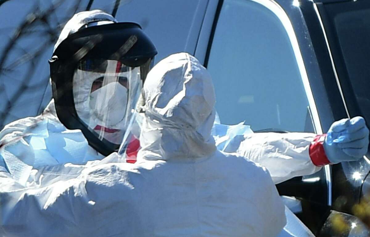 Workers with Murphy Medical Associates conduct corona virus at a drive-thru testing station Tuesday, March 24, 2020, at Bedford Middle School in Westport, Conn. Due to a large coronavirus outbreak in Westport, the Westport Weston Health District arranged for additional community testing. Residents of Westport and Weston were tested by Murphy Medical Associates, a private company, from 8:30 a.m. to noon.