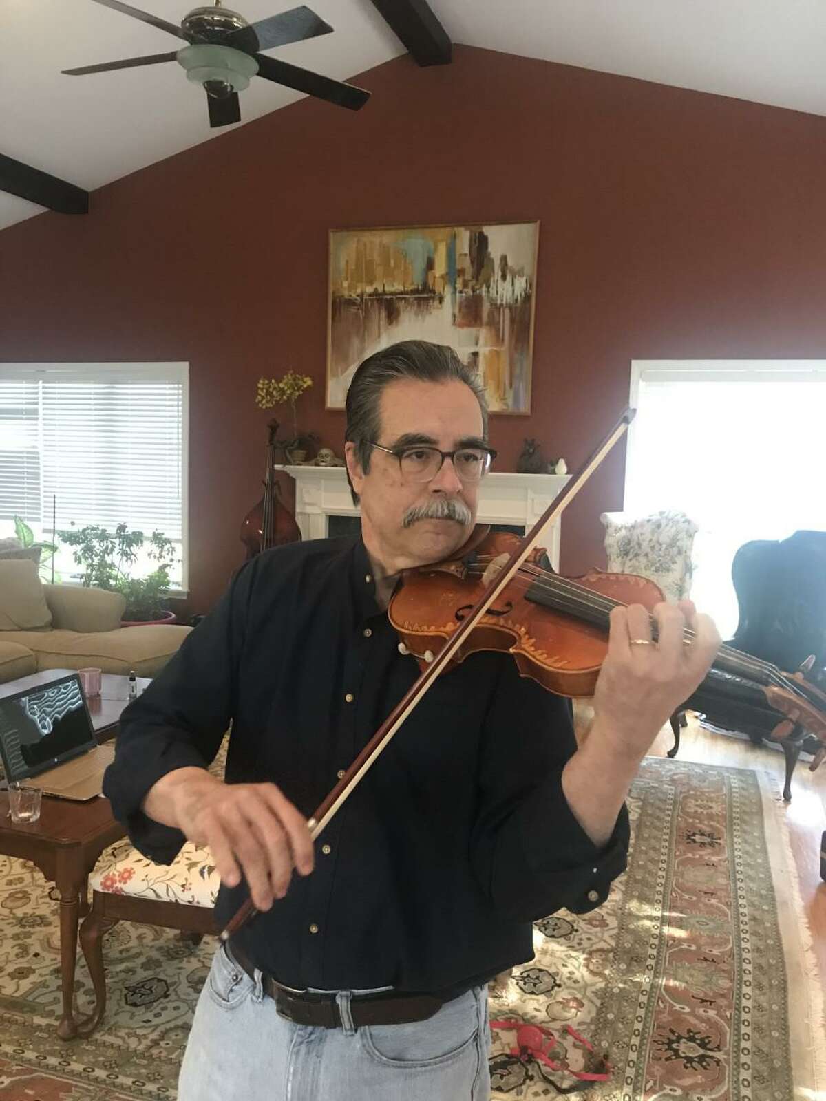 Mac Johnston plays the violin in his living room in Wilton.