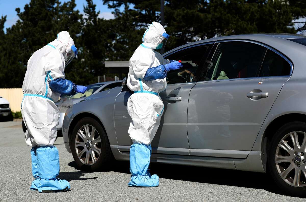Medical professionals administer a coronavirus (COVID-19) test during a drive-thru testing station on March 26, 2020 in Daly City, California. New coronavirus testing stations are opening up each day in the San Francisco Bay Area.