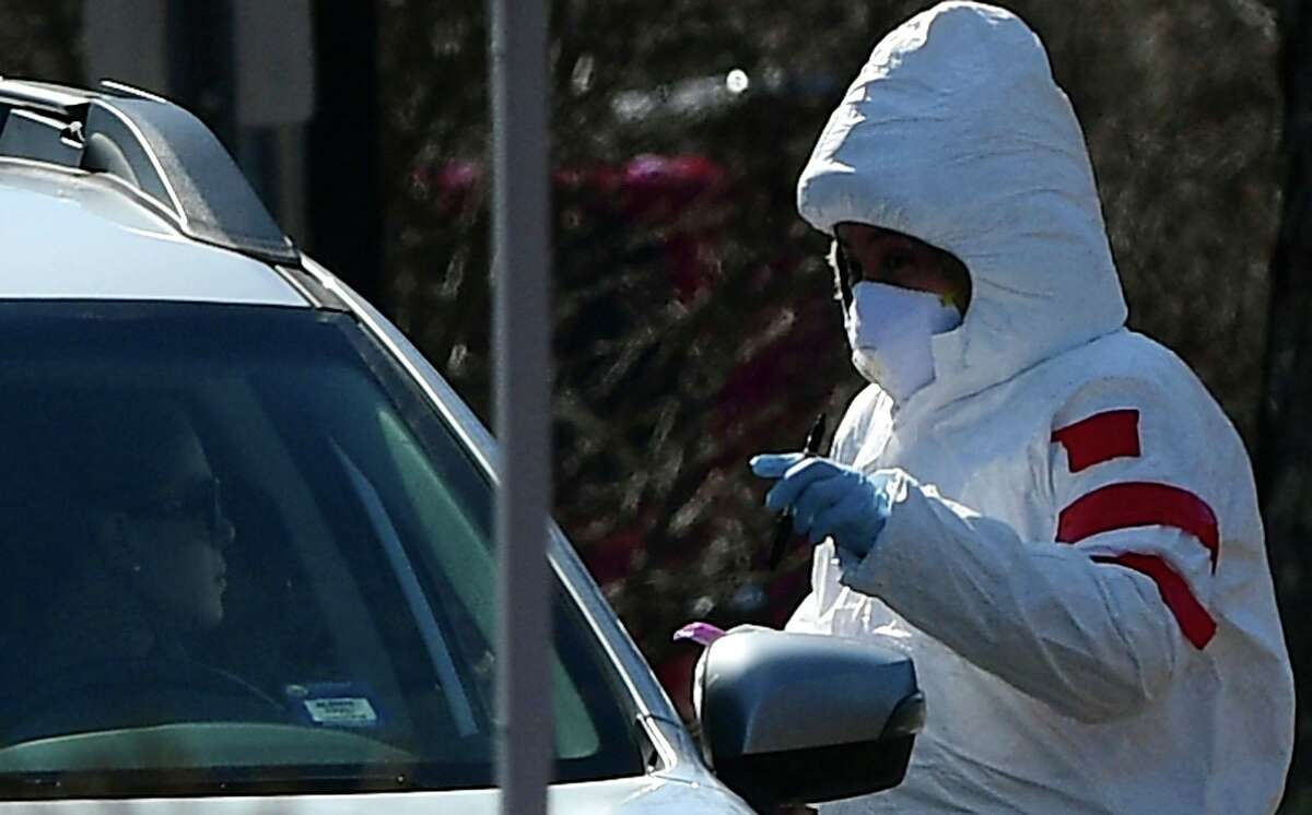 Workers with Murphy Medical Associates conduct corona virus at a drive-thru testing station Tuesday, March 24, 2020, at Bedford Middle School in Westport, Conn. Due to a large coronavirus outbreak in Westport, the Westport Weston Health District arranged for additional community testing. Residents of Westport and Weston were tested by Murphy Medical Associates, a private company, from 8:30 a.m. to noon.