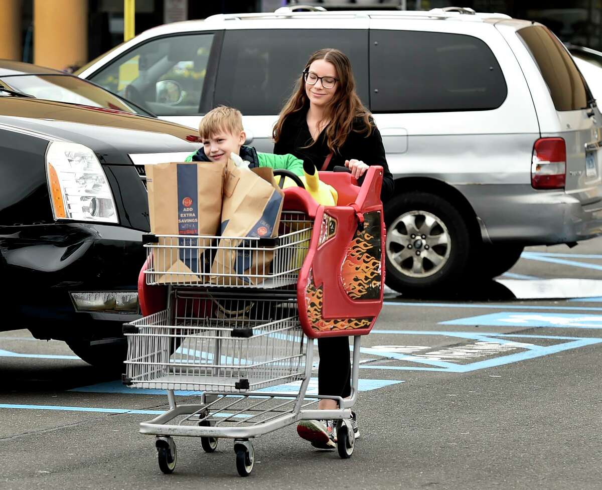 Angela Hunt, who was quarantined as an unconfirmed case of coronavirus but has been cleared to resume her life by the East Shore District Health Department, returns to her car Monday after going grocery shopping at the Big Y Supermarket in Branford with her son Vincent Hunt, 6.