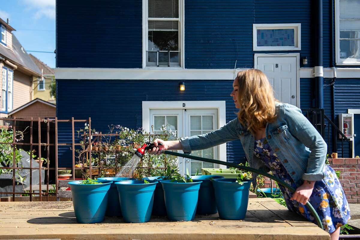 Tiffany Keller, a furloughed flight attendant, watering her garden behind her apartment building on March 24, 2020 in Alameda, Calif.