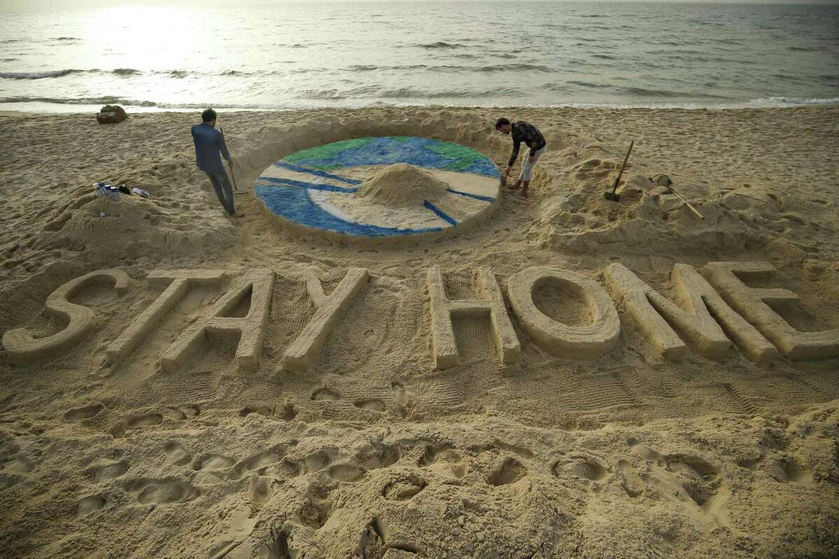 Palestinian artists work on a sand sculpture depicting the earth with a message reading "Stay Home" along a beach in Gaza City during the COVID-19 coronavirus pandemic, on March 31, 2020. (Photo by MOHAMMED ABED / AFP) (Photo by MOHAMMED ABED/AFP via Getty Images)