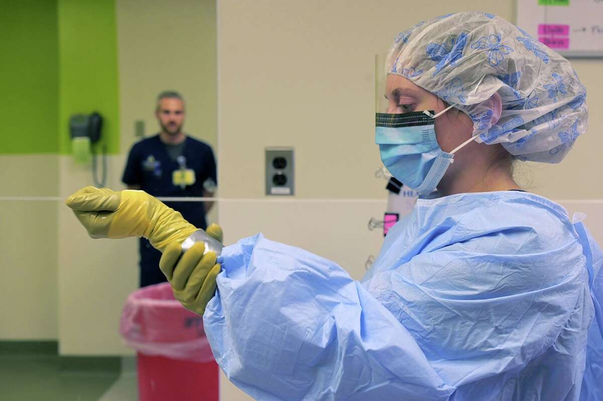 Samuel Gutner, a superior of the biocontainment unit watches lead clinical nurse Madeleine Steinberg rub hand sanitizer on her outer set of gloves which are sealed with tape as medical staff train at Johns Hopkins Hospital on Jan. 28, 2020. (Karl Merton Ferron/Baltimore Sun/TNS)