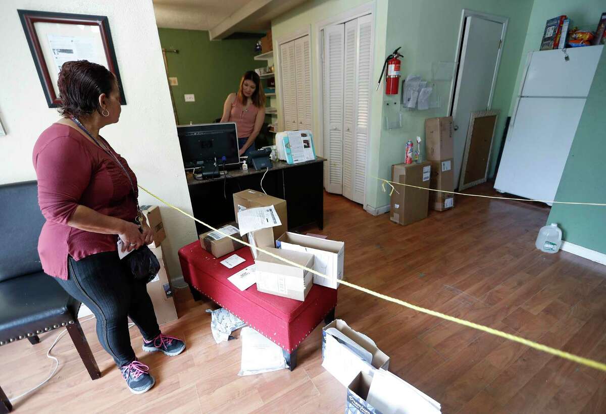A tenant of the Westview Forest apartment complex stands across a barrier for safety inside of the leasing office at the in Houston, Monday, March 30, 2020. Landlord Jack Yetiv set up the two ropes to keep people at a safe distance due to the coronavirus pandemic.
