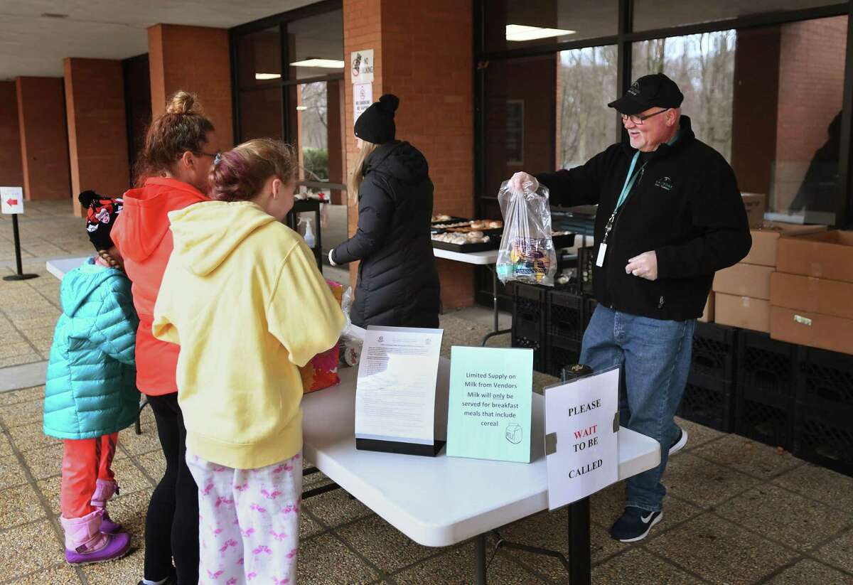 Rich Sandmann, executive chef with Whitsons Culinary Group, school food provider for the Shelton school system, hands out bagged lunches and breakfasts to a family outside Shelton High School in Shelton, Conn. on Tuesday, March 31, 2020.