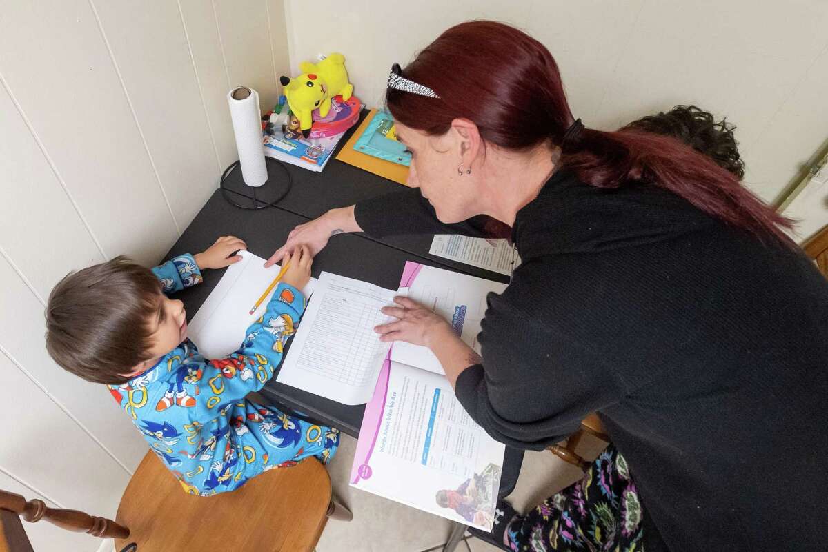 Jacoby Crisp, 6, gets instruction from his mom on his kindergarten work at their home. Amber Feener has three kids in Port Necehs-Groves schools and homeschooling during the Covid-19 pandemic began for all of them on Wednesday, March 25, 2020. Fran Ruchalski/The Enterprise