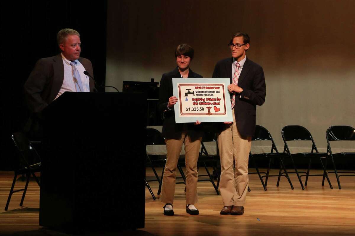 Glenholme School in Washington recently celebrated its quarterly donation to flintkids.org. Above, Glenholme teacher Andrew Kepics, left, presents the check to Anna T. and Andrew D. for funds raised for children in Flint.