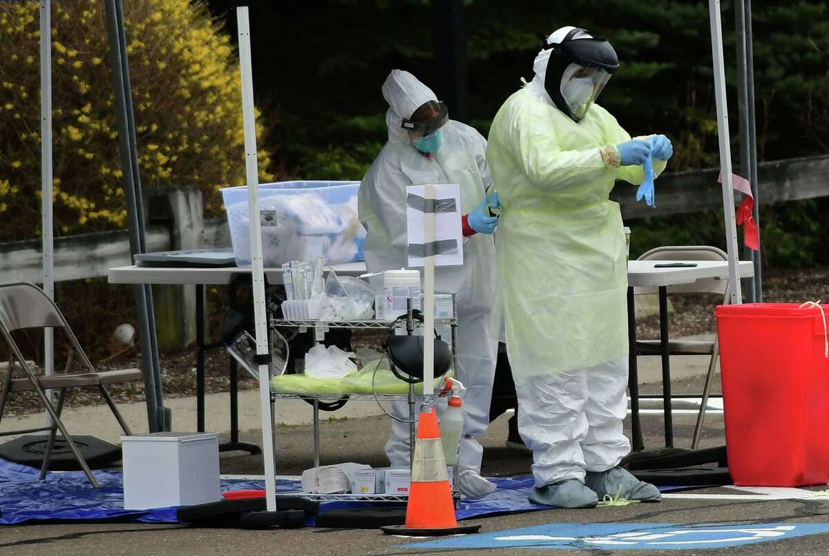 Workers with Murphy Medical Associates conduct corona virus at a drive-thru testing station Tuesday, March 31, 2020, at Bedford Middle School in Westport, Conn. Due to a large coronavirus outbreak in Westport, the Westport Weston Health District arranged for additional community testing. Residents of Westport and Weston were tested by Murphy Medical Associates, a private company, from 8:30 a.m. to noon.