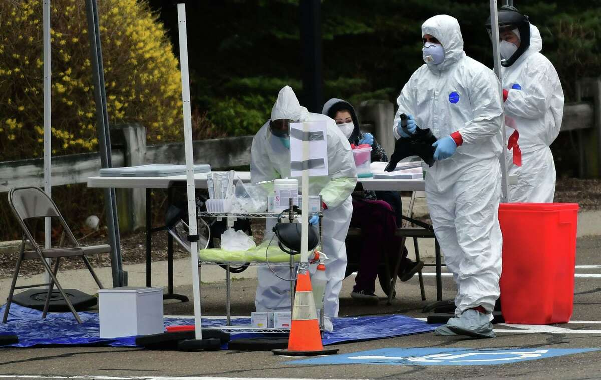 Workers with Murphy Medical Associates conduct corona virus at a drive-thru testing station Tuesday, March 31, 2020, at Bedford Middle School in Westport, Conn. Due to a large coronavirus outbreak in Westport, the Westport Weston Health District arranged for additional community testing. Residents of Westport and Weston were tested by Murphy Medical Associates, a private company, from 8:30 a.m. to noon.