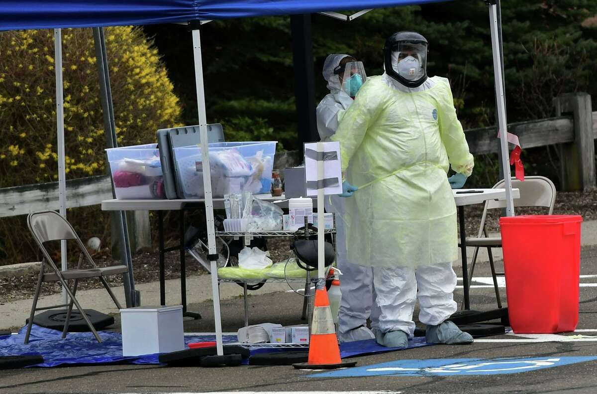 Workers with Murphy Medical Associates conduct corona virus at a drive-thru testing station Tuesday, March 31, 2020, at Bedford Middle School in Westport, Conn. Due to a large coronavirus outbreak in Westport, the Westport Weston Health District arranged for additional community testing. Residents of Westport and Weston were tested by Murphy Medical Associates, a private company, from 8:30 a.m. to noon.