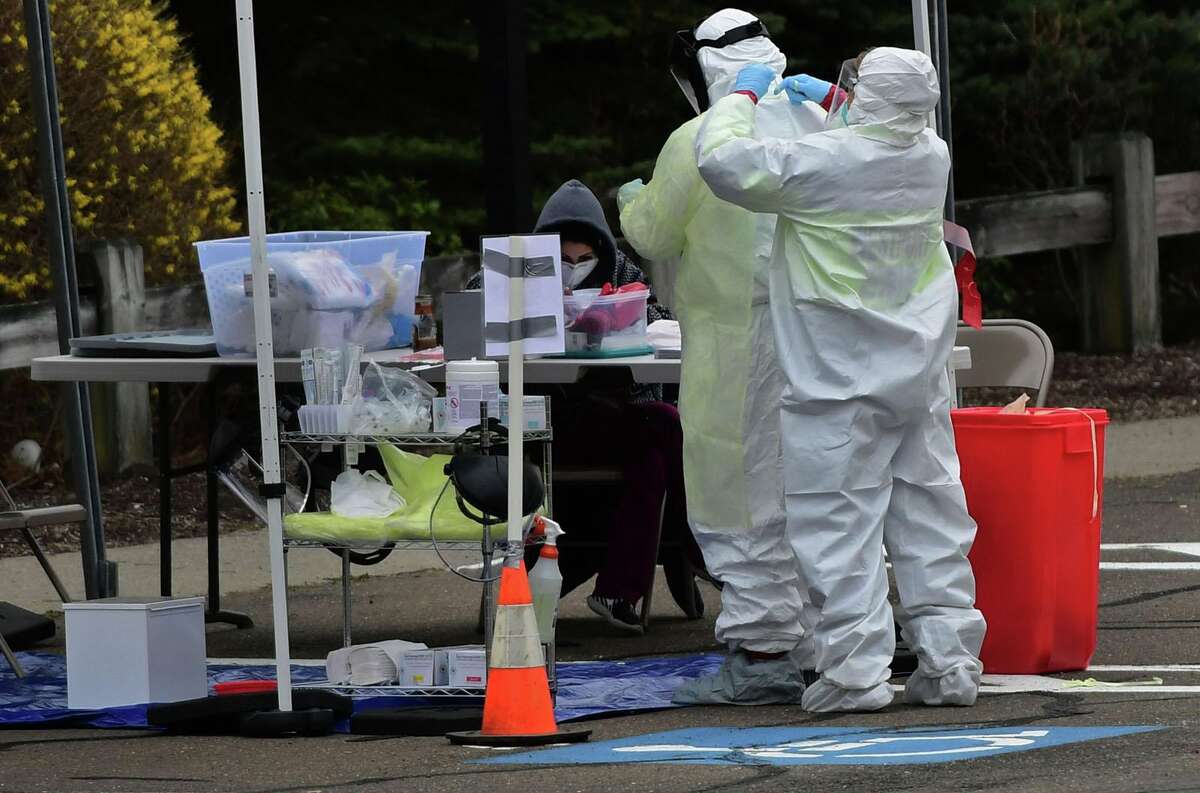 Workers with Murphy Medical Associates conduct corona virus at a drive-thru testing station Tuesday, March 31, 2020, at Bedford Middle School in Westport, Conn. Due to a large coronavirus outbreak in Westport, the Westport Weston Health District arranged for additional community testing. Residents of Westport and Weston were tested by Murphy Medical Associates, a private company, from 8:30 a.m. to noon.