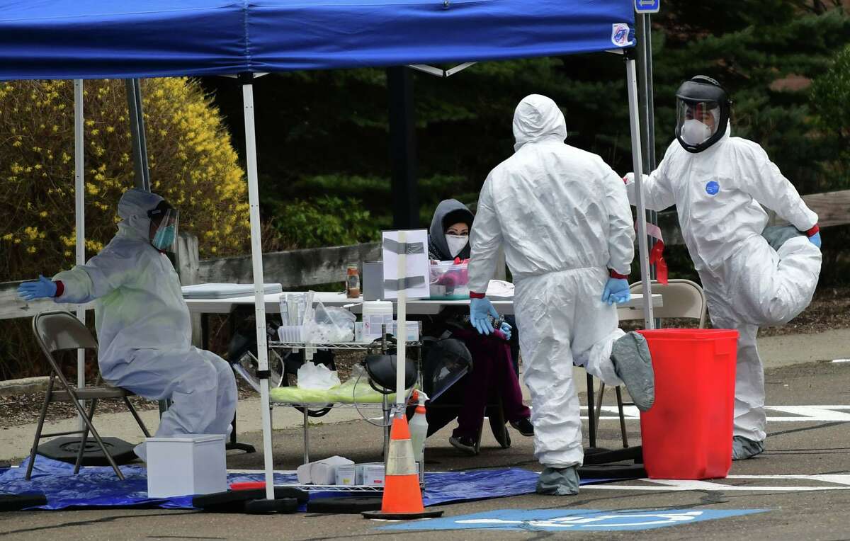 Workers with Murphy Medical Associates conduct corona virus at a drive-thru testing station Tuesday, March 31, 2020, at Bedford Middle School in Westport, Conn. Due to a large coronavirus outbreak in Westport, the Westport Weston Health District arranged for additional community testing. Residents of Westport and Weston were tested by Murphy Medical Associates, a private company, from 8:30 a.m. to noon.
