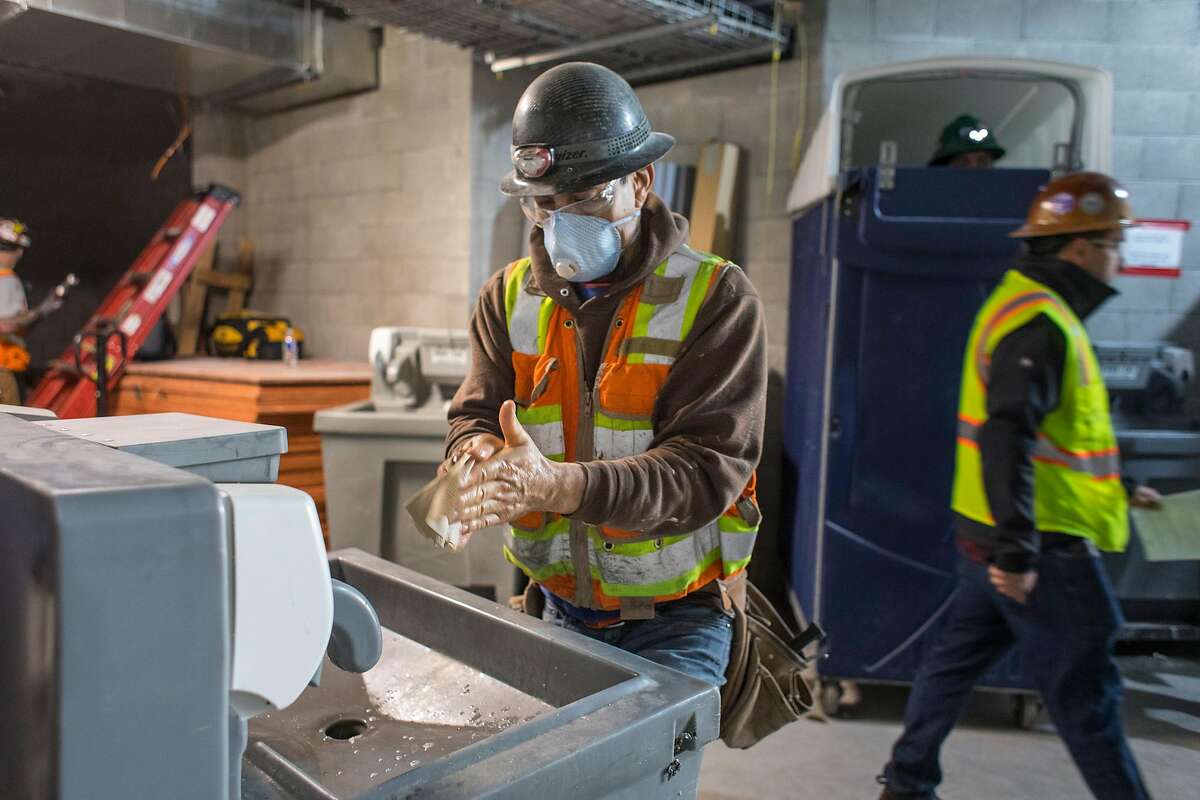 Jesus Camacho washes his hands at a cleaning station on a construction site for a new housing project at 950 Gough Street on Tuesday, March 31, 2020 in San Francisco, Calif.