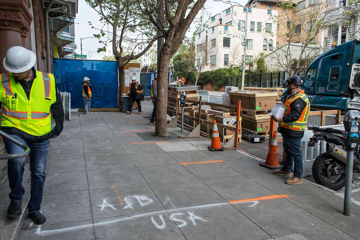 Lines on the street mark spots where workers can stand six feet apart before entering a new housing project at 950 Gough Street on Tuesday, March 31, 2020 in San Francisco, Calif.