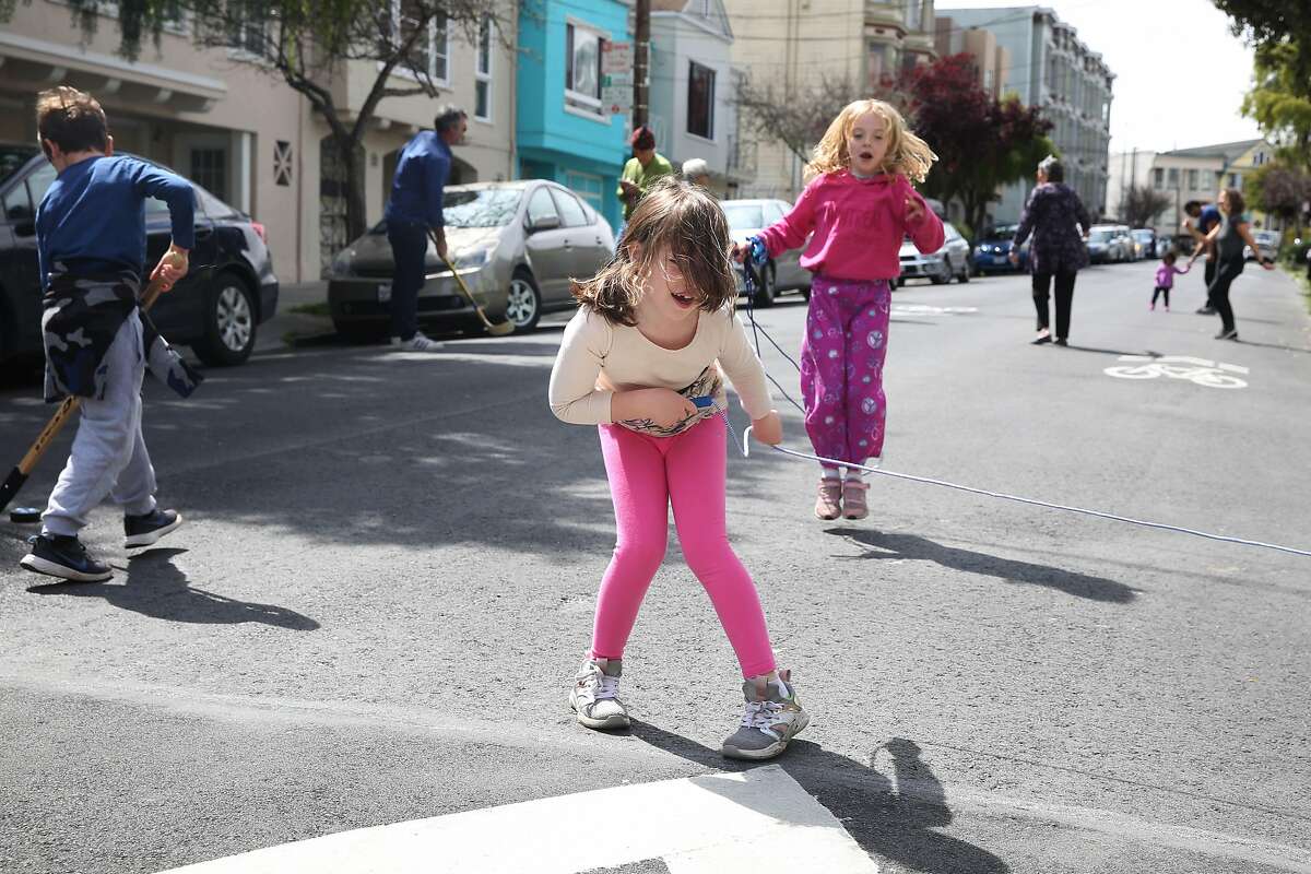 Sofia Rae (center), 7, swings a jump rope as Francesca Oram (right), 7, leaps over it as they and their neighbors enjoy a fifteen minute dance party while practicing social distancing on Tiffany Street on Tuesday, March 31, 2020 in San Francisco, Calif.