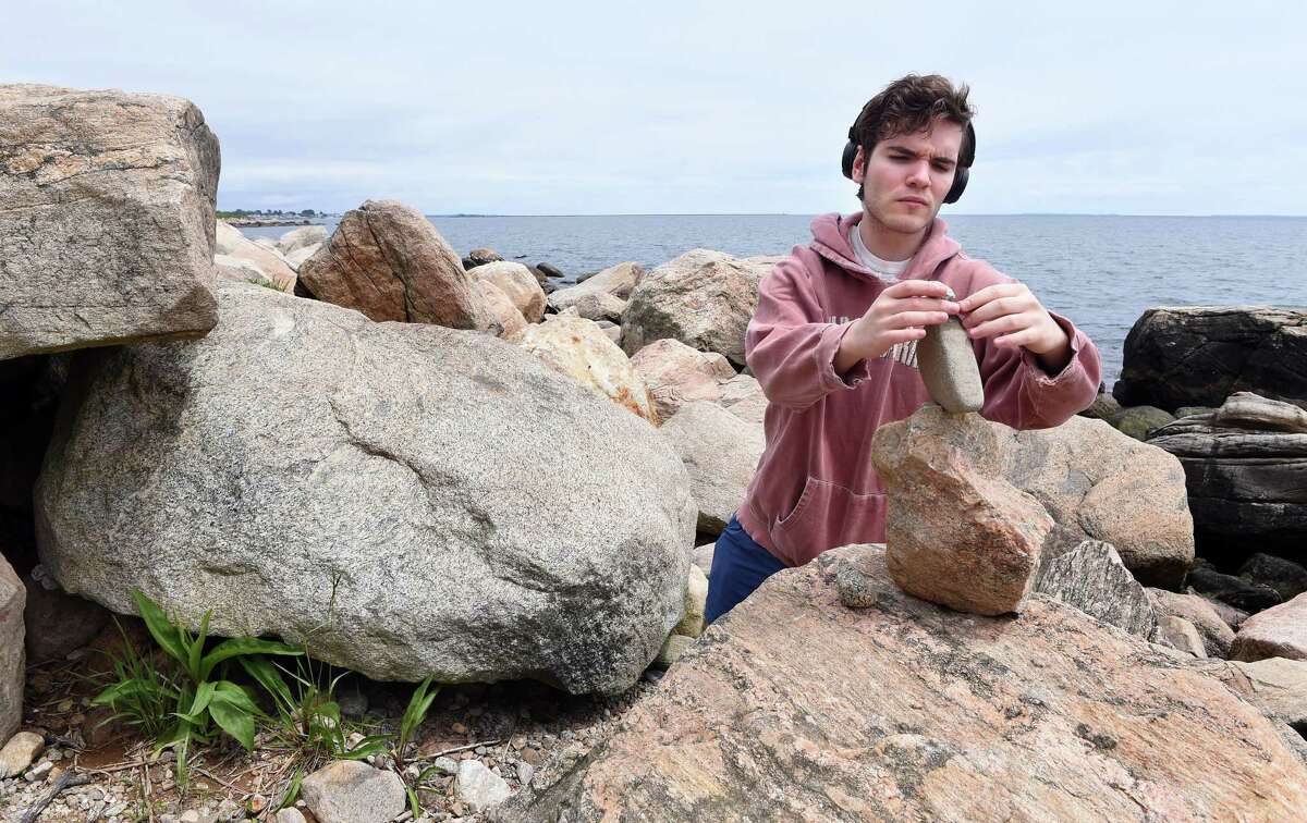 Edmund Rogers of Guilford creates a rock sculpture by balancing rocks on each other amongst the boulders at Hammonasset Point at Hammonasset Beach State Park in Madison on May 29, 2019.