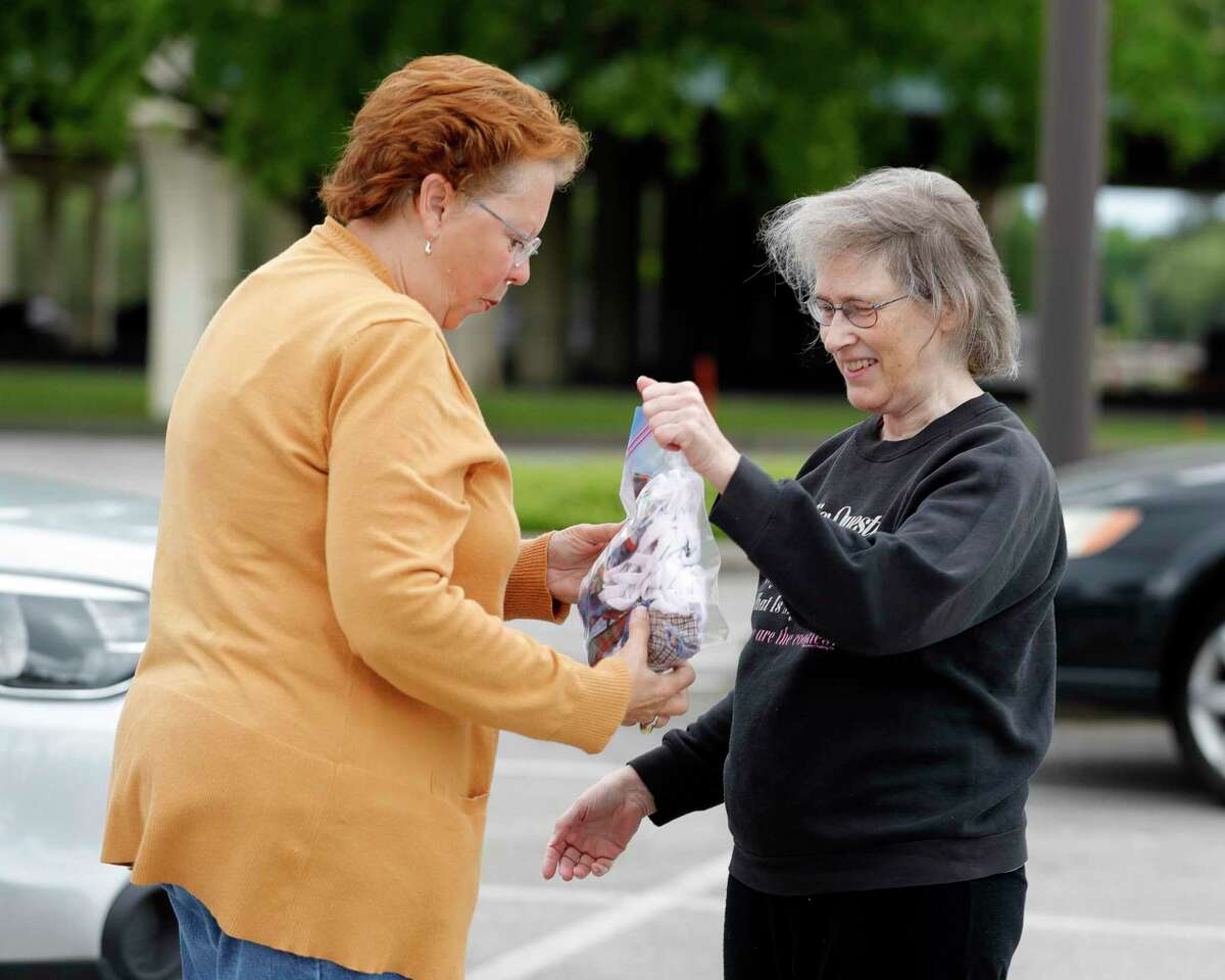 Jane Carver, president of the Golden Needles Quilt Guild, takes a bag full of hand-made masks from Diane Miller, Tuesday, March 31, 2020, in Conroe. The organization collected more than 200 hand-made masks from its members to be given to Tri-County Service for its medical workers