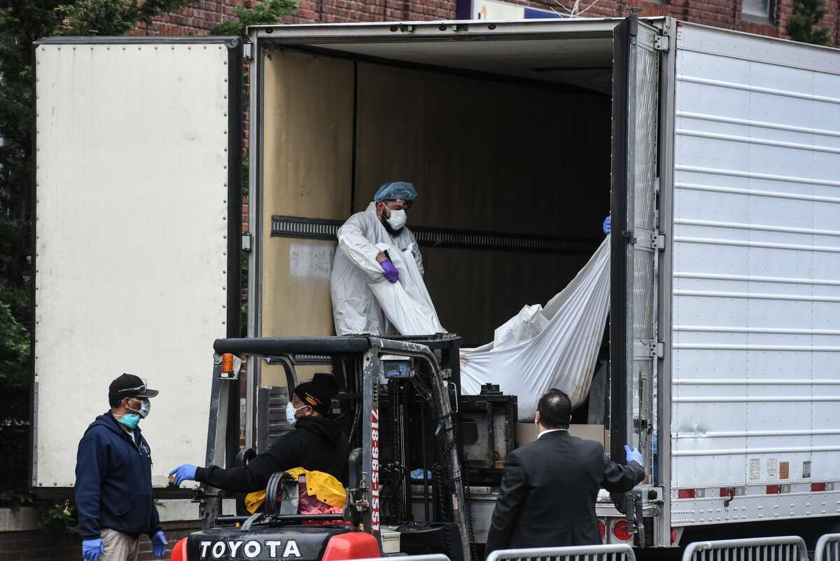 Medical workers bring a body to a refrigerated truck outside of the Brooklyn Hospital on March 31, 2020 in New York City. Due to a surge in deaths caused by the Coronavirus, hospitals are using refrigerated trucks as make shift morgues. (Photo by Stephanie Keith/Getty Images)