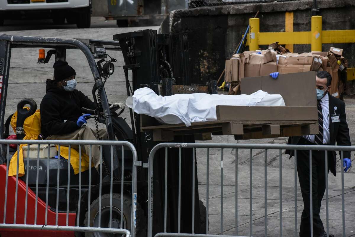 A worker uses a forklift to move a body outside of the Brooklyn Hospital on March 31, 2020 in New York, United States. Due to a surge in deaths caused by the Coronavirus, hospitals are using refrigerator trucks as make shift morgues. (Photo by Stephanie Keith/Getty Images)