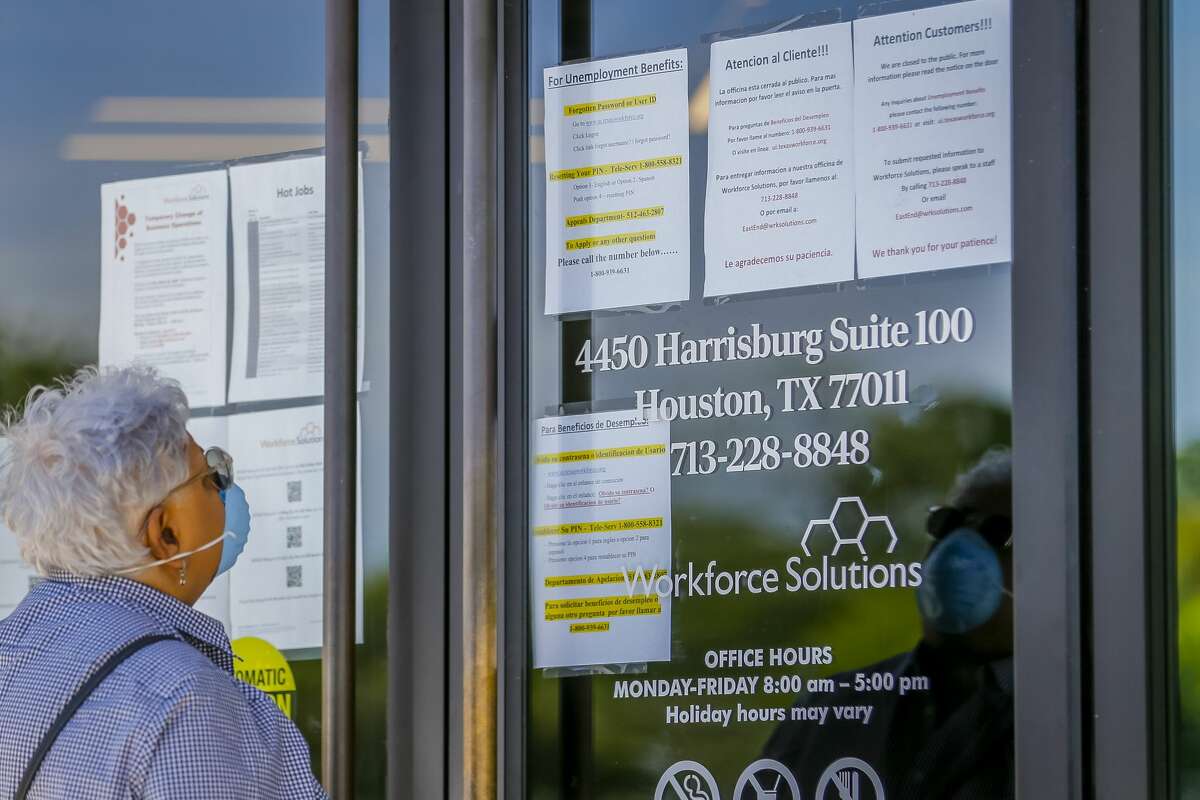 A woman looks at the signs saying that the Workforce Solutions office is closed due to the Covid-19 outbreak, Wednesday, April 1, 2020, on Harrisburg in east Houston. Services are still available online and by phone, but the physical office is closed.