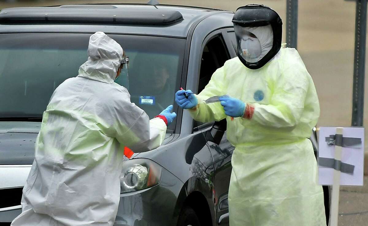 Workers with Murphy Medical Associates conduct corona virus at a drive-thru testing station Tuesday, March 31, 2020, at Bedford Middle School in Westport, Conn. Due to a large coronavirus outbreak in Westport, the Westport Weston Health District arranged for additional community testing. Residents of Westport and Weston were tested by Murphy Medical Associates, a private company, from 8:30 a.m. to noon.