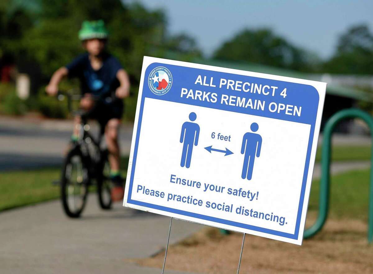 A sign reminds visitors at Dennis Johnston Park to practice social distancing, Thursday, March 27, 2020, in Spring.