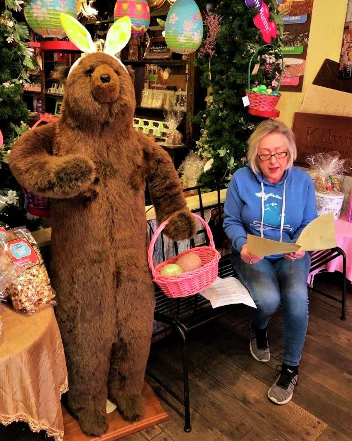 Old Pioneer Store and Kilwins Big Rapids co-owner Carlleen Rose reads a book created by a local child. Rose is inviting area children to create their own books while they practice social distancing in their homes. All participants will receive a gift and a free pizza when they come to pick up their book. (Courtesy photo)