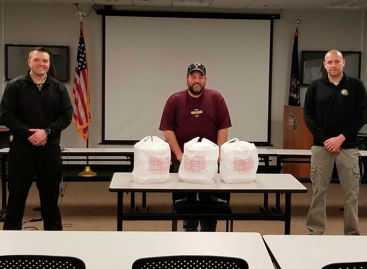 Josh Sagala (center) of Chopos Northside Bar delivers food to the Manistee County Sheriff's Office on Wednesday. It was the first delivery of the program the Salt City Rock & Blues group is doing to thank those who are working during the coronavirus pandemic to help the public by using local restaurants to prepare food for them. The group has a GoFundMe site on their Facebook page where people can donate to the cause. (Courtesy photo)