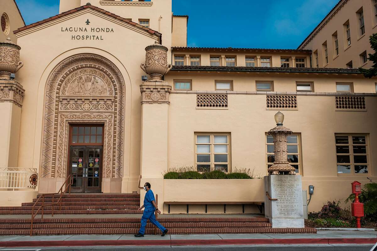 Hospital personnel walks past the front of Laguna Honda Hospital in San Francisco, Calif. on Tuesday March 31, 2020.