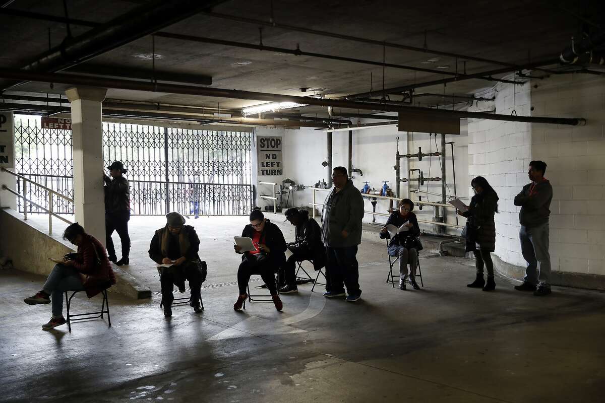 Unionized hospitality workers wait in line in a basement garage to apply for unemployment benefits at the Hospitality Training Academy Friday, March 13, 2020, in Los Angeles. Fearing a widespread health crisis, Californians moved broadly Friday to get in front of the spread of the coronavirus, shuttering schools that educate hundreds of thousands of students, urging the faithful to watch religious services online and postponing or scratching just about any event that could attract a big crowd. (AP Photo/Marcio Jose Sanchez)