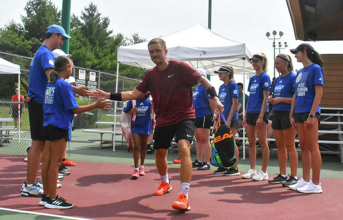 Nathan Ponwith is welcomed by the ball kids before the start of his Edwardsville Futures singles championship match.