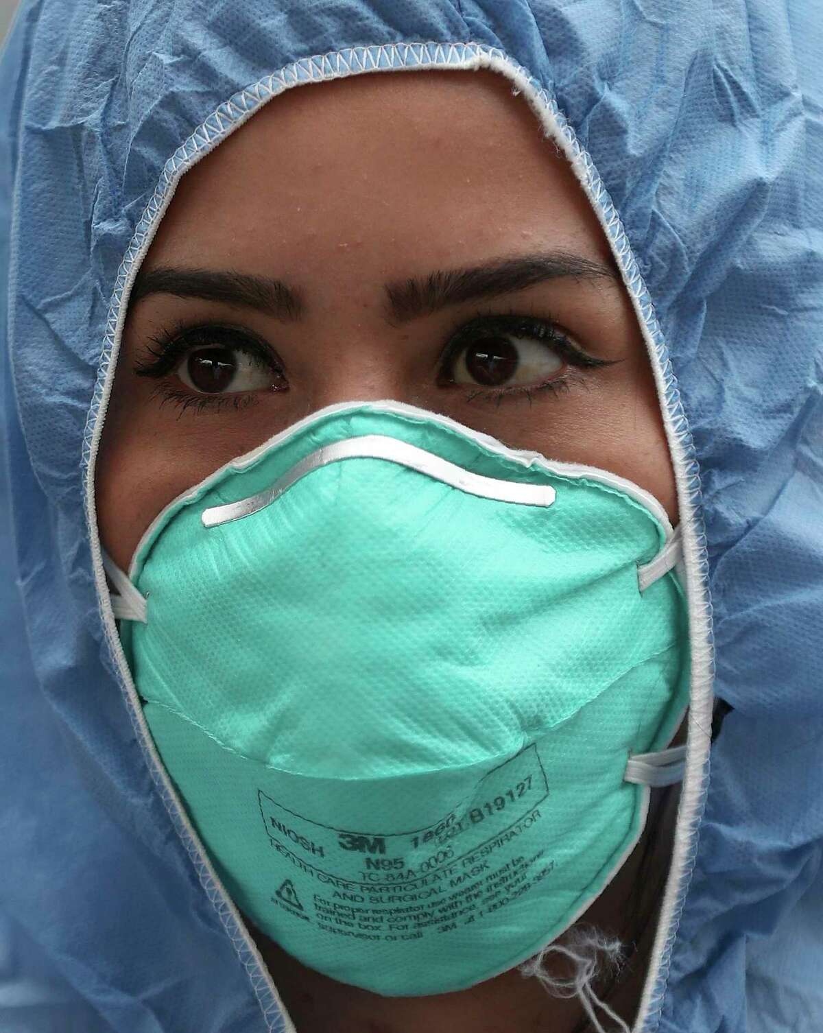 Una enfermera, vestida con ropa protectora como medida de precaución contra el nuevo coronavirus, espera mientras revisa la temperatura de los viajeros en un puesto de control afuera de una estación de autobuses en Soacha, en las afueras de Bogotá, Colombia, el miércoles 1 de abril de 2020. (AP Foto/Fernando Vergara)