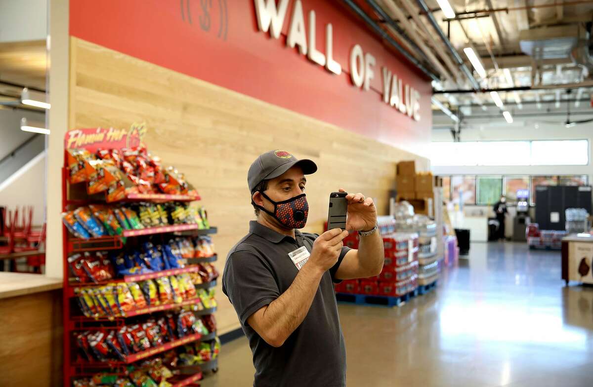Brahm Ahmadi, CEO, snaps images of items that need pricing at Community Foods Market, located at 3105 San Pablo Ave., on Thursday, April 2, 2020, in Oakland, Calif.