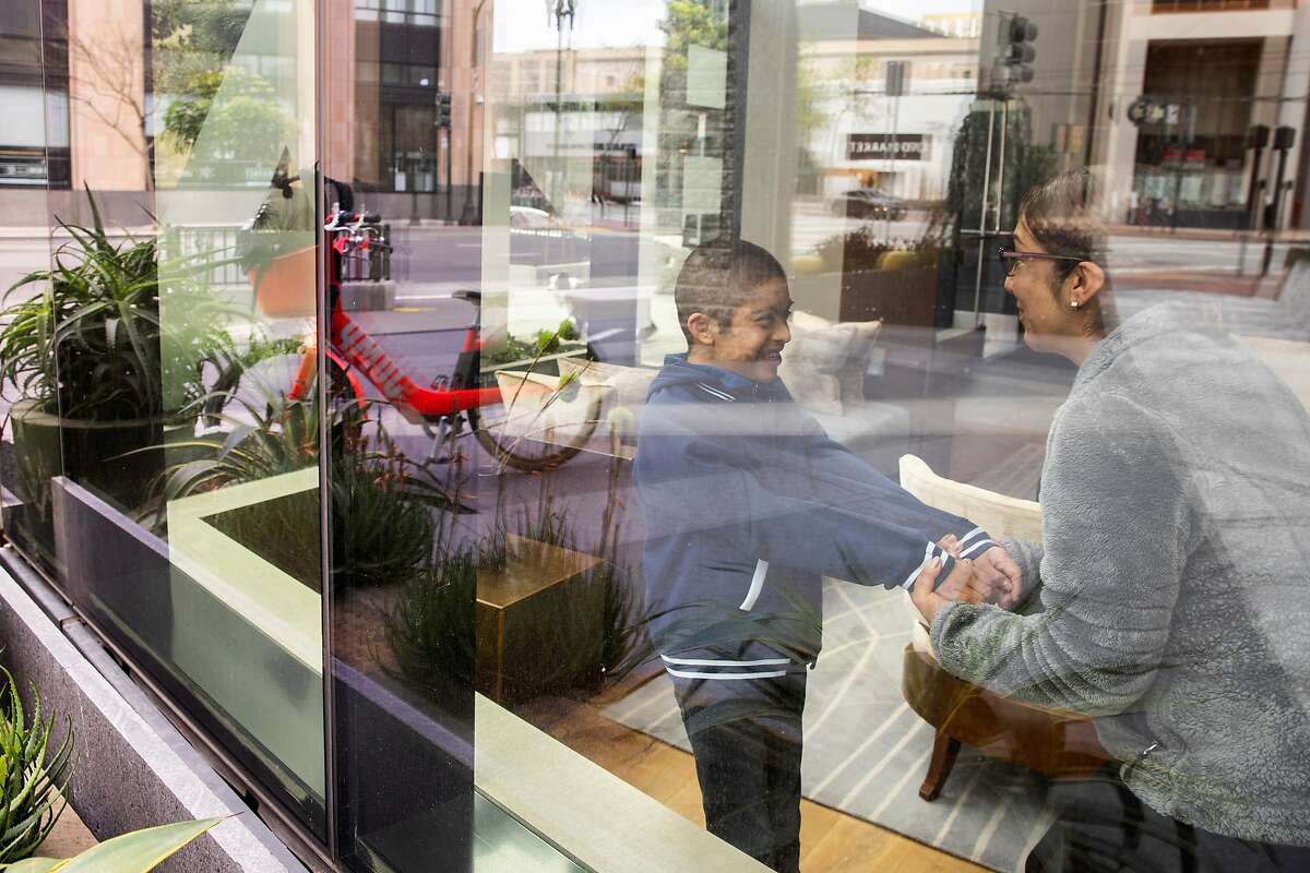 Olivia Fraga (right) and her ten-year-old son Martin Perez-Fraga at their apartment lobby on Tuesday, March 31, 2020, in San Francisco, Calif. With schools closed because of coronavirus pandemic, Martin is no longer receiving all the services he would get at school. Martin has Down syndrome.