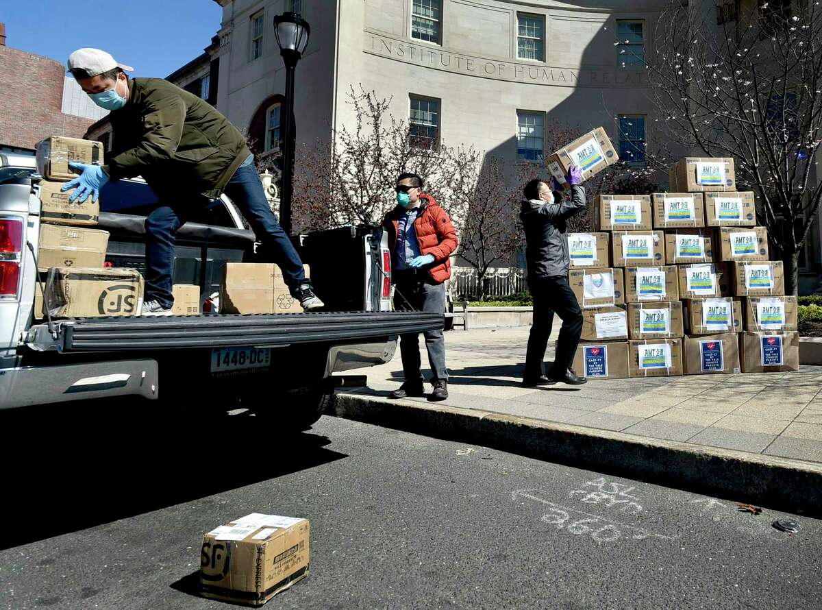 Jason Zhao of Orange, left, Qi Xue of Woodbridge, center, and Jiankan Guo of Cheshire, right, a Yale research scientist in nephrology and president of the Chinese Association of Science and Technology’s Connecticut Chapter, stack boxes of personal protective eqipment Thursday before a press conference in front of the Yale School of Medicine in New Haven.