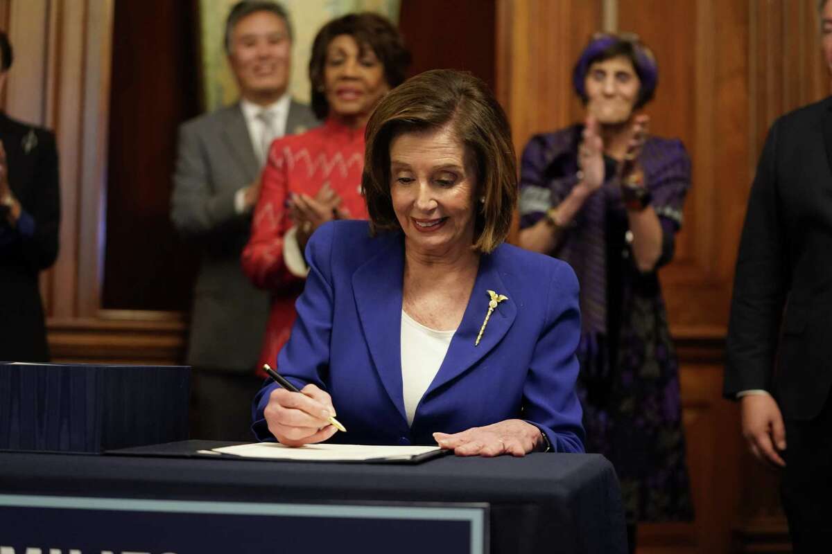 U.S. Speaker of the House Nancy Pelosi signs the CARES ACT on March 27, 2020, after the House approved it by a voice vote. With its passage, columnist Michael Taylor says, the United States is neck-deep in a massive experiment based on Modern Monetary Theory, which supports a massive intervention of the government in the economy in times of trouble.