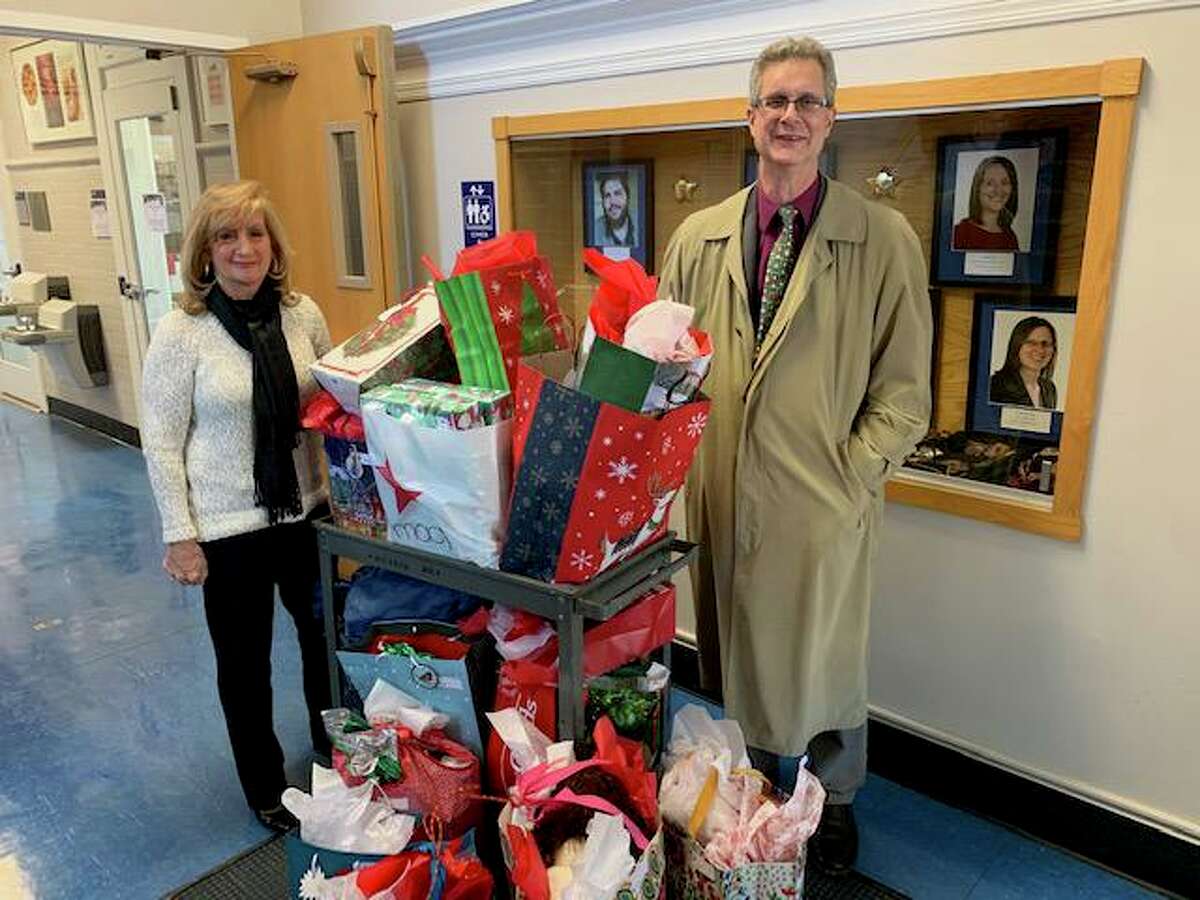Operations Manager Angela Flynn and Associate Dean Michael J. Rossi of the College of Arts and Sciences at the University of New Haven flank a cart of gift bags recently. The UNH college partnered this year with city Youth and Family Services Director Robert S. Morton to adopt a West Haven family for the holidays. Under the leadership of Flynn and interim Dean Elizabeth Ann Beaulieu, the college collected toys, clothes, books and other donations from more than 20 people for a deserving family.