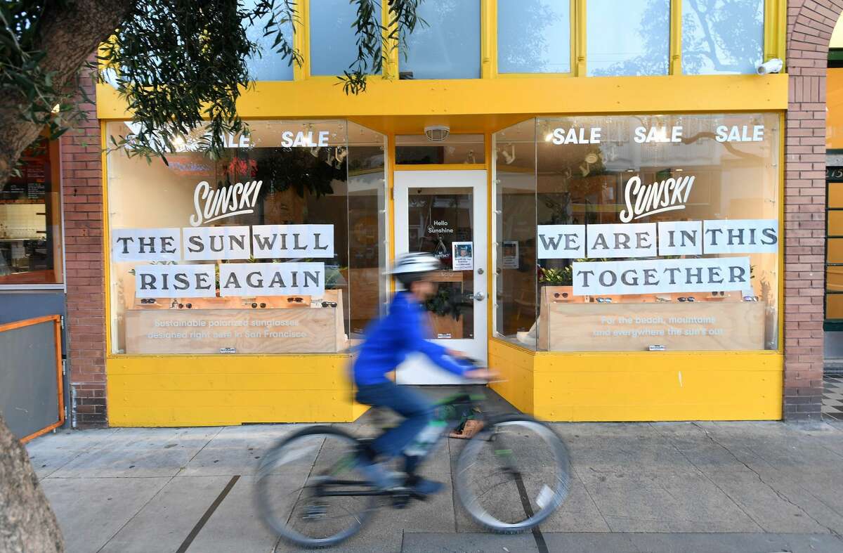 A boy rides his bike passed a supportive sign posted on a storefront in San Francisco on April, 1, 2020, during the novel coronavirus outbreak.
