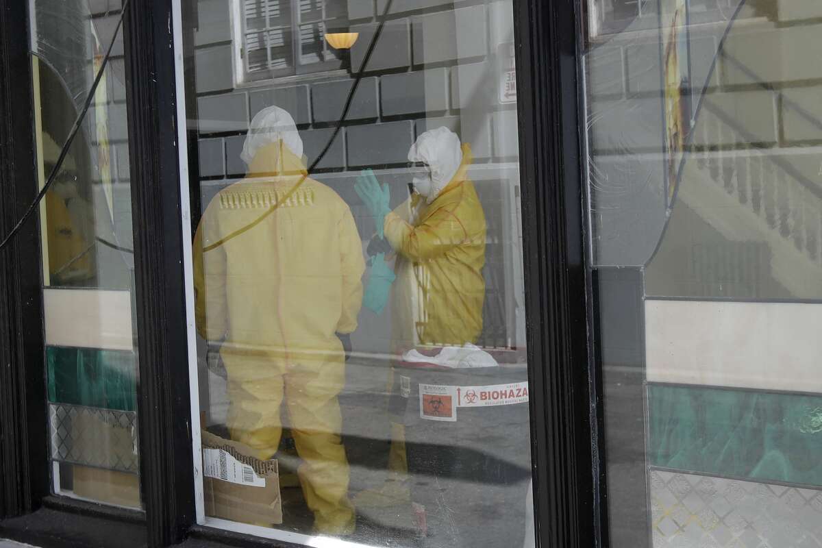 Men in hazardous material suits work inside the Abigail Hotel in San Francisco, Thursday, April 2, 2020. The hotel is one of several private hotels San Francisco has contracted with to take vulnerable people who show symptoms or are awaiting test results for the coronavirus.