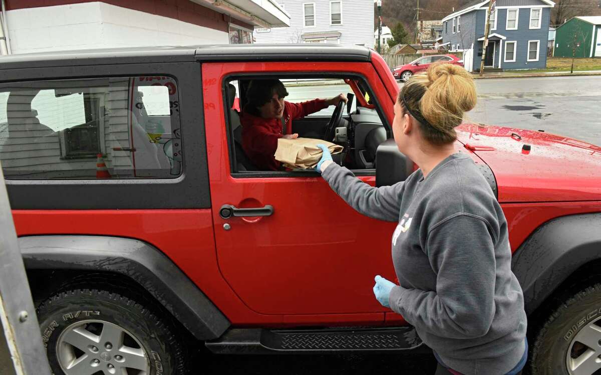 Christine Murphy is seen serving customers in their car out of the Snowman-to-go trailer parked behind the main ice cream stand on Friday, April 3, 2020 in Troy, N.Y. Her husband and owner of Snowman, John Murphy, carefully set up everything to deal with social distancing but was forced to close when people ignored the safeguards. He's allowing pre-ordered pickup and trying to figure out how to reopen. (Lori Van Buren/Times Union)